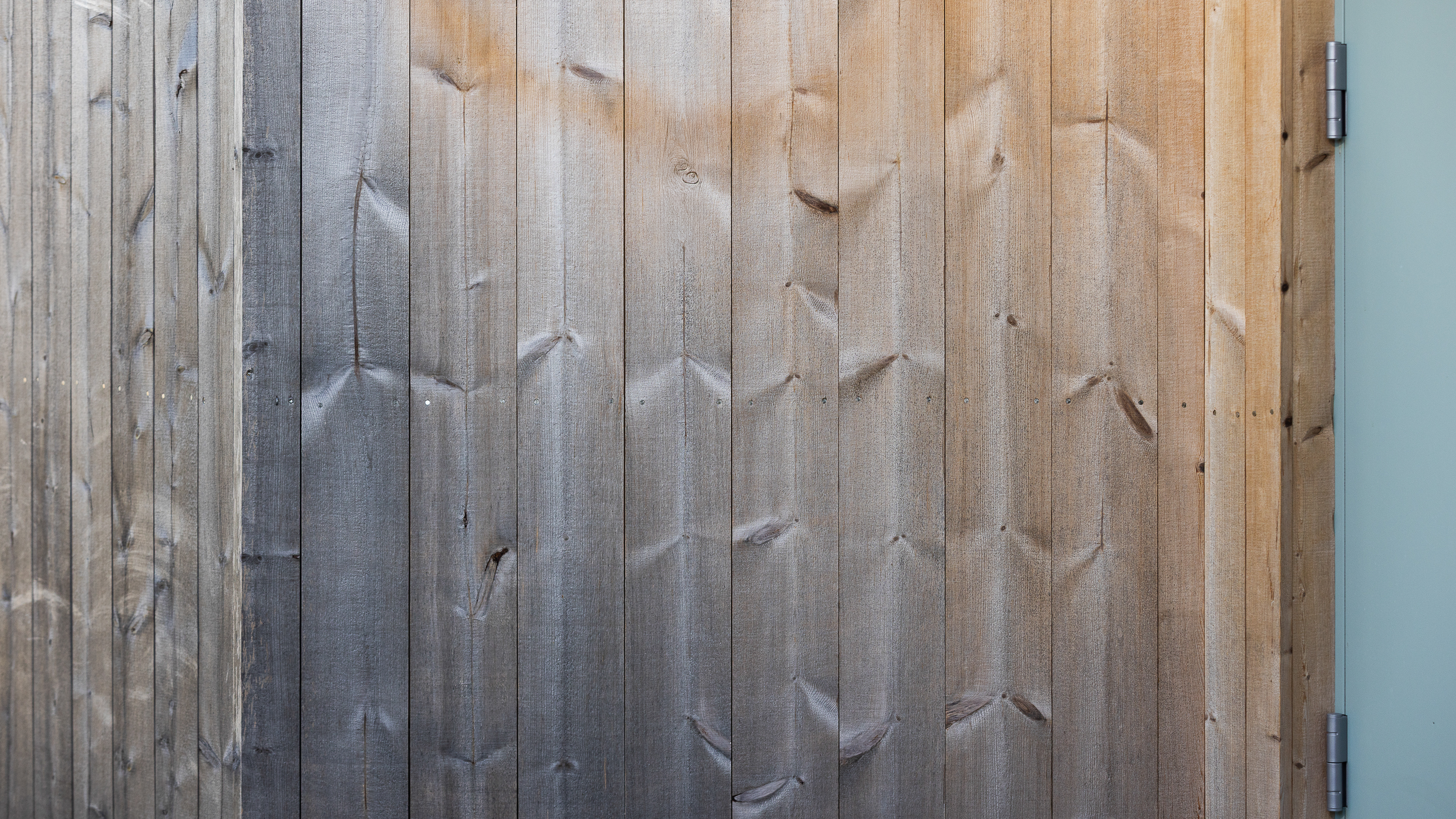 Sliten vegg i malmfuru med ujevn gråning, før behandling med TREBITT Woodcare.