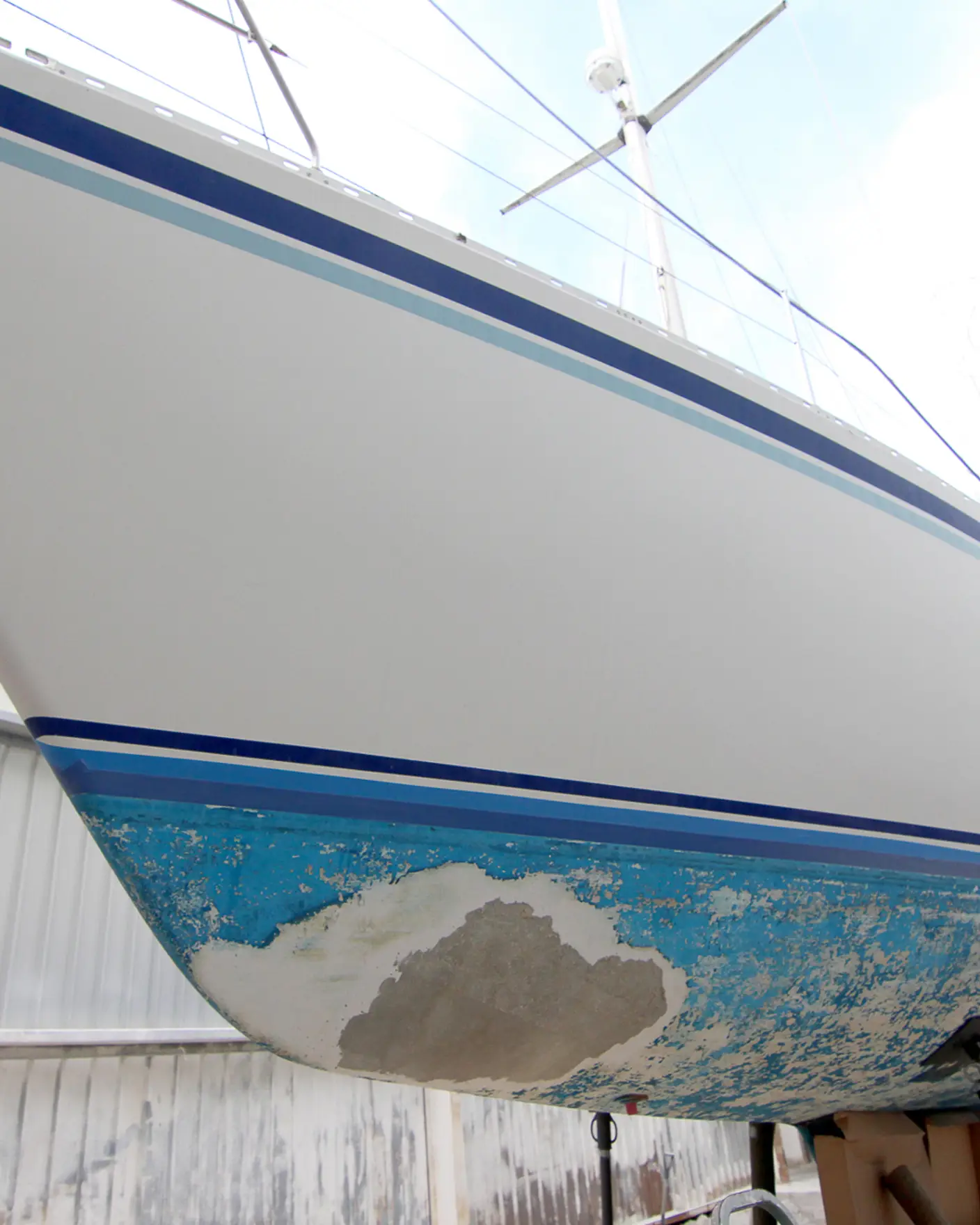 Båt med slitent skrog på bukker klart for pussing og vedlikehold med Jotuns båt-produkter.