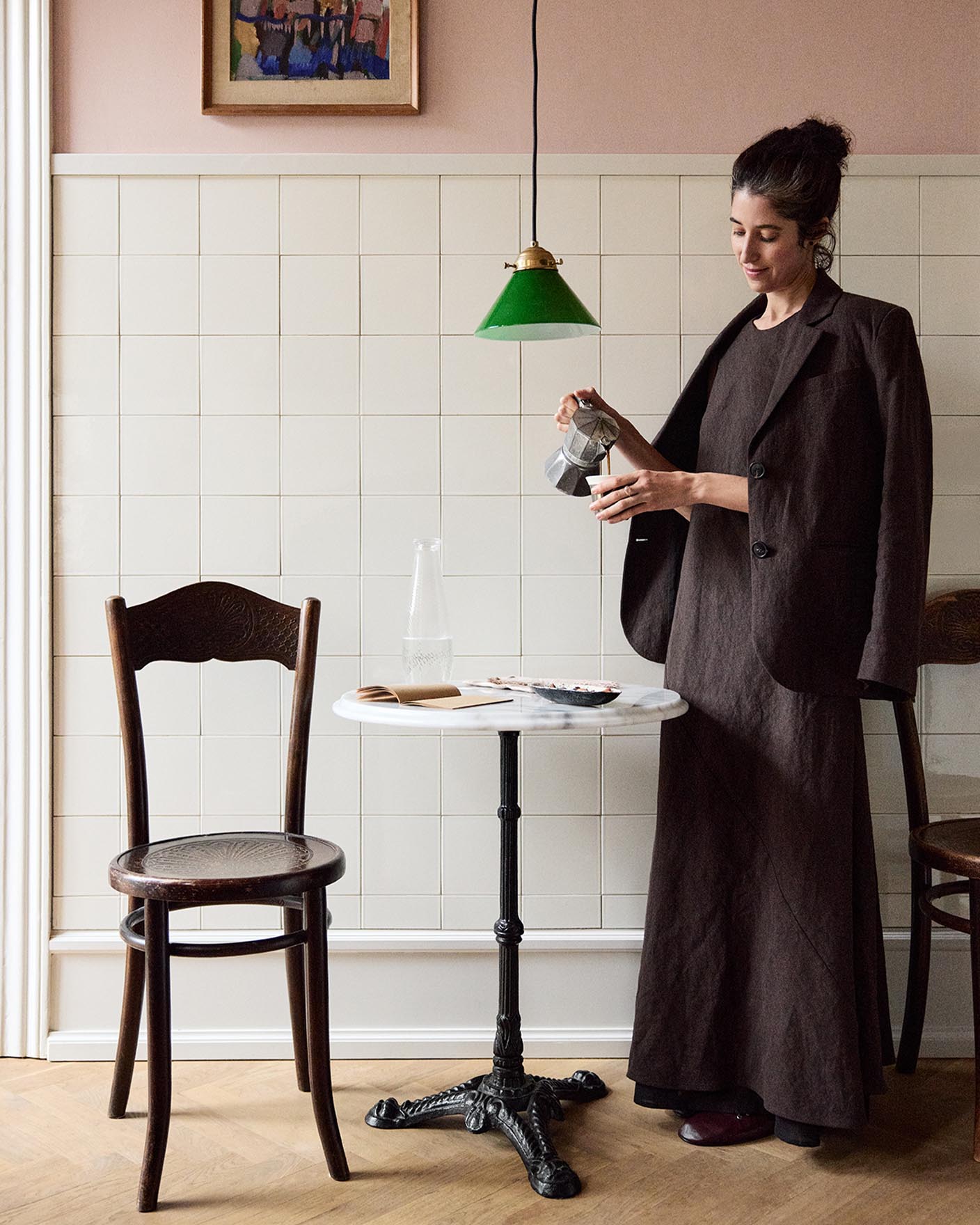 Woman standing in front of a tiled wall. The upper wall is painted in the soft pink colour Jotun 20362 Pink Ambience. 