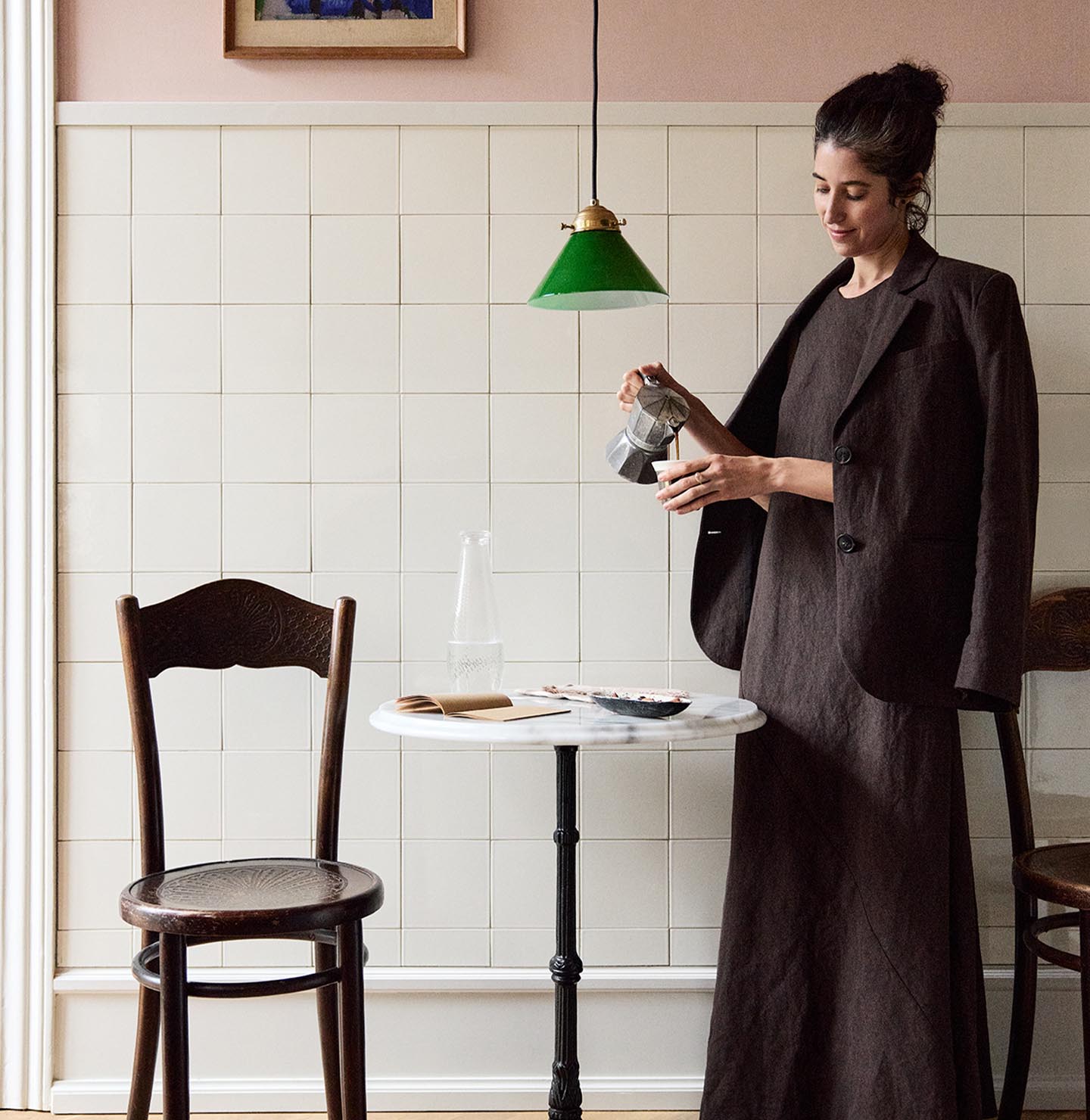 Woman standing in front of a tiled wall. The upper wall is painted in the soft pink colour Jotun 20362 Pink Ambience. 