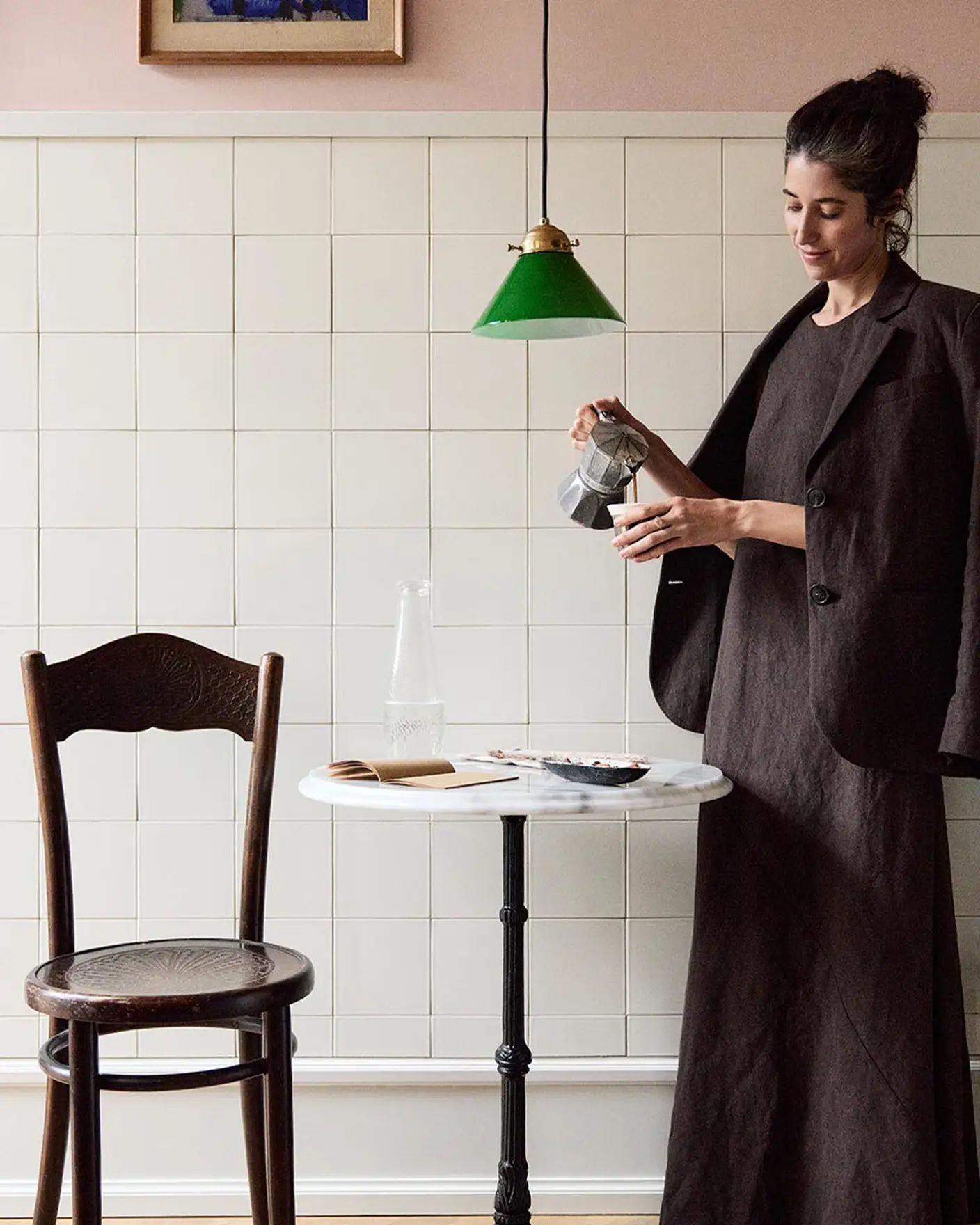 Woman standing in front of a tiled wall. The upper wall is painted in the soft pink colour Jotun 20362 Pink Ambience.