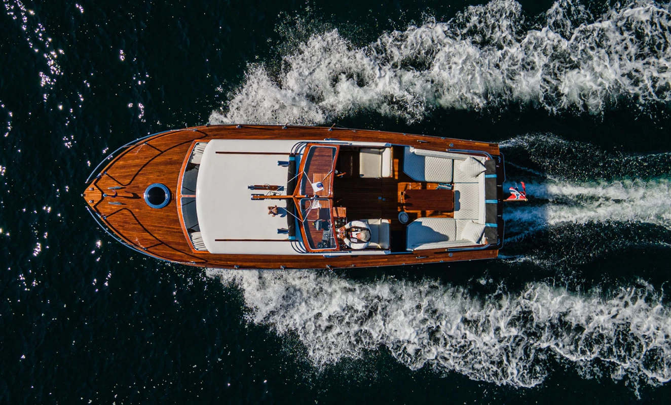 Trebåt sett ovenfra som kjører i høy fart og lager tydelig kjølvann.