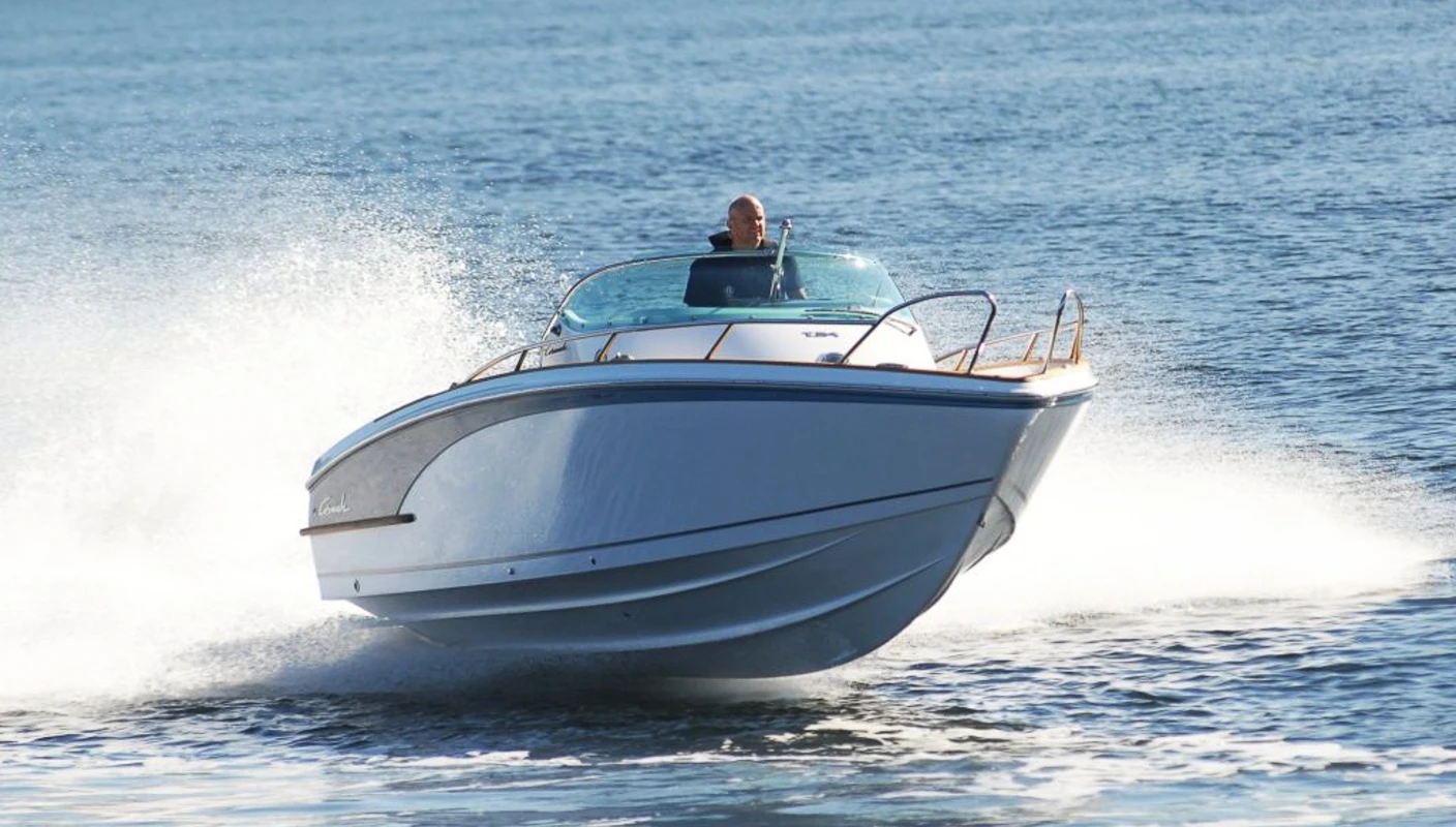 Mann styrer blank fritidsbåt i full fart på sjøen