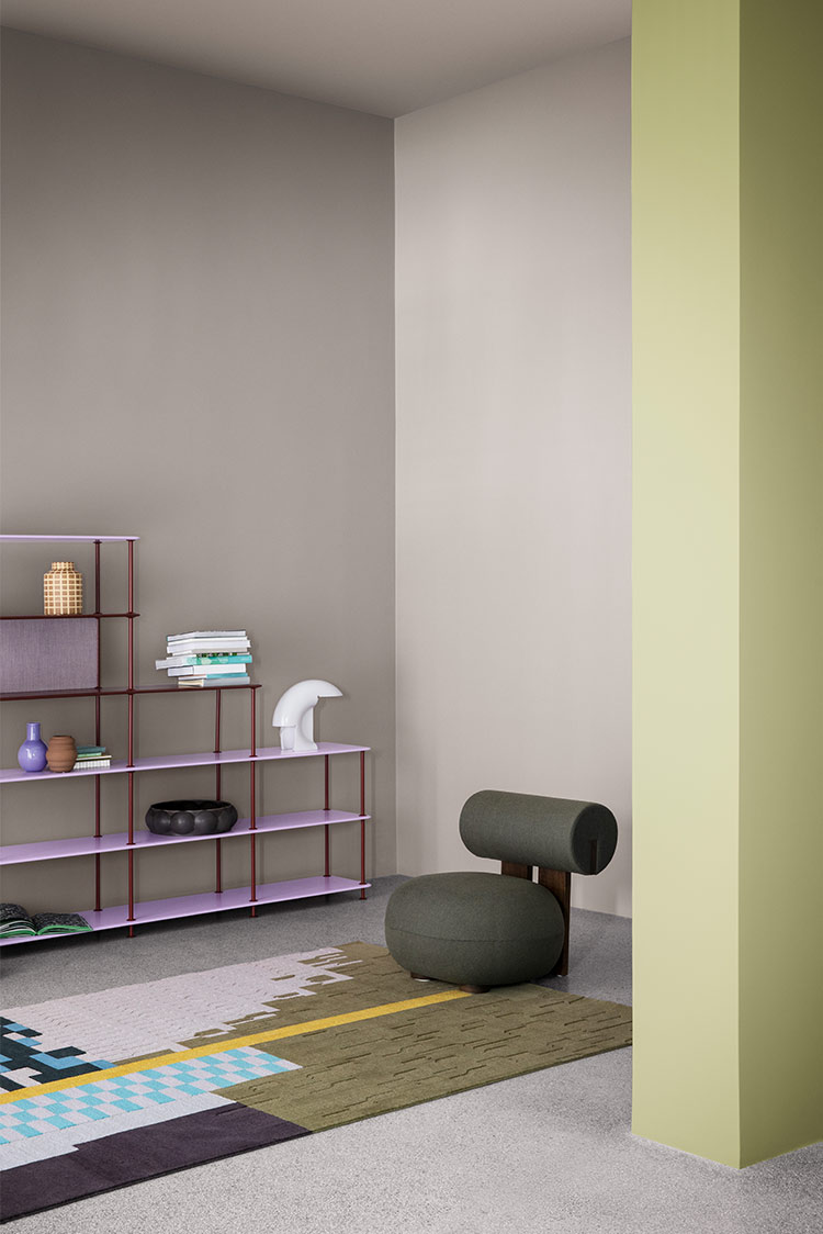 Moderne minimalistisk stue med en grå lenestol, teppe med geometrisk mønster, lys lilla hylleenhet og dekorative gjenstander mot lavendelfargede og pastellgule vegger, malt i Jotun 20186 Lavender Touch og 8565 Hope
