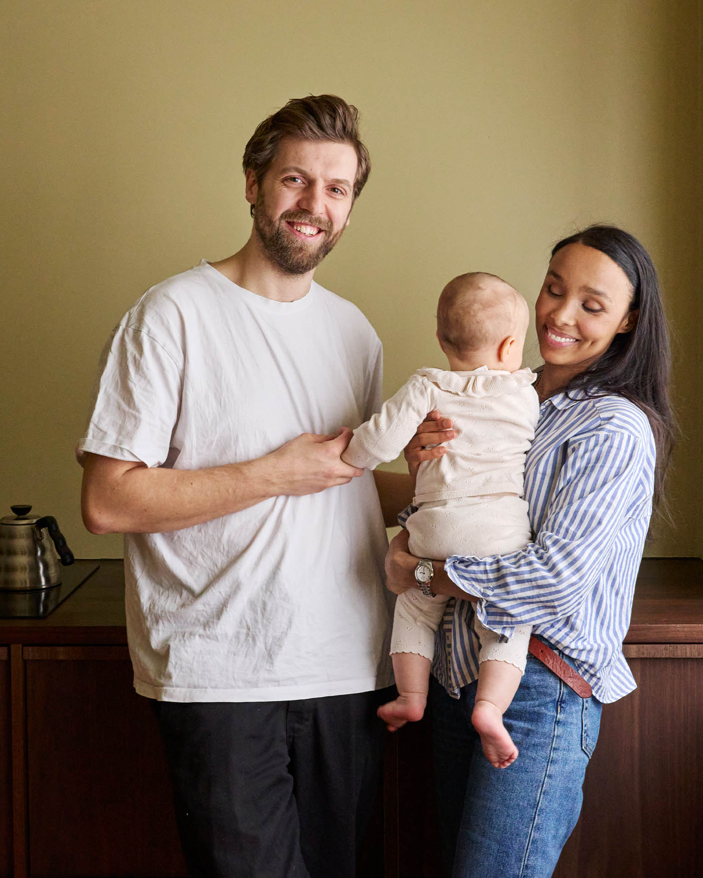 Family in front of wall painted with Jotun LADY 8583 Earthy Yellow. Soft beige background with warm tones, creating a cozy and welcoming atmosphere